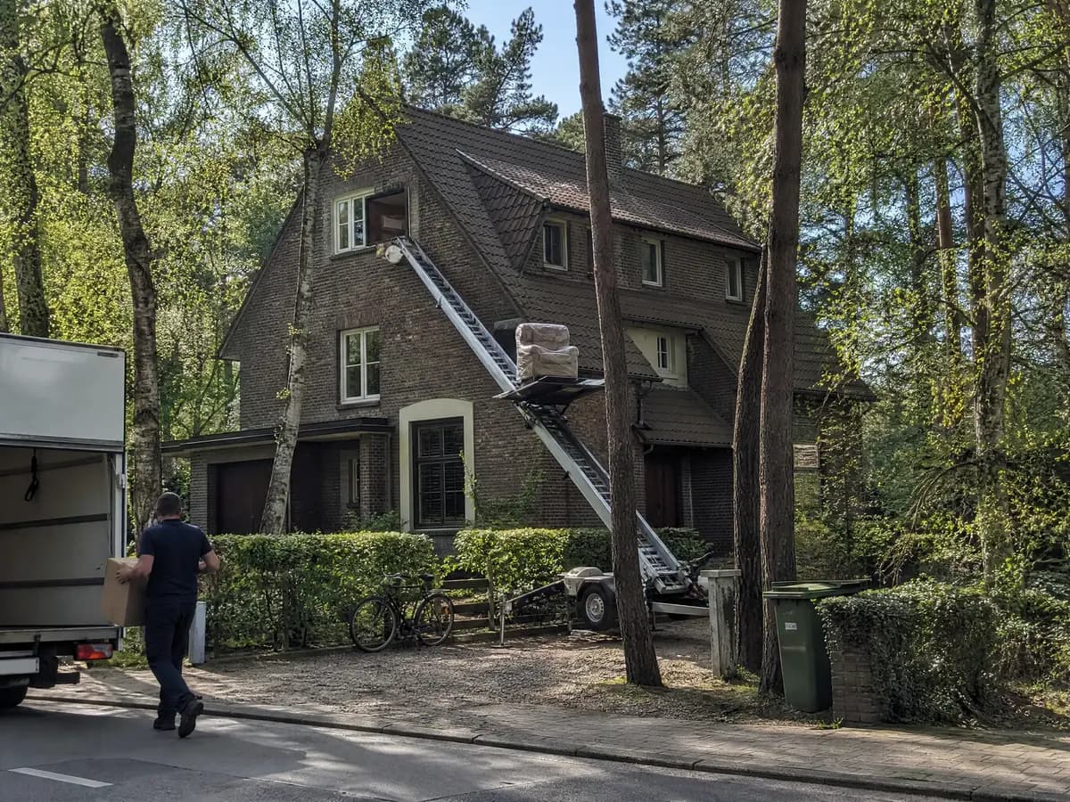 Verhuisfirma Kalmthout: ladderlift met meubels aan het raam van een woning in Kalmthout