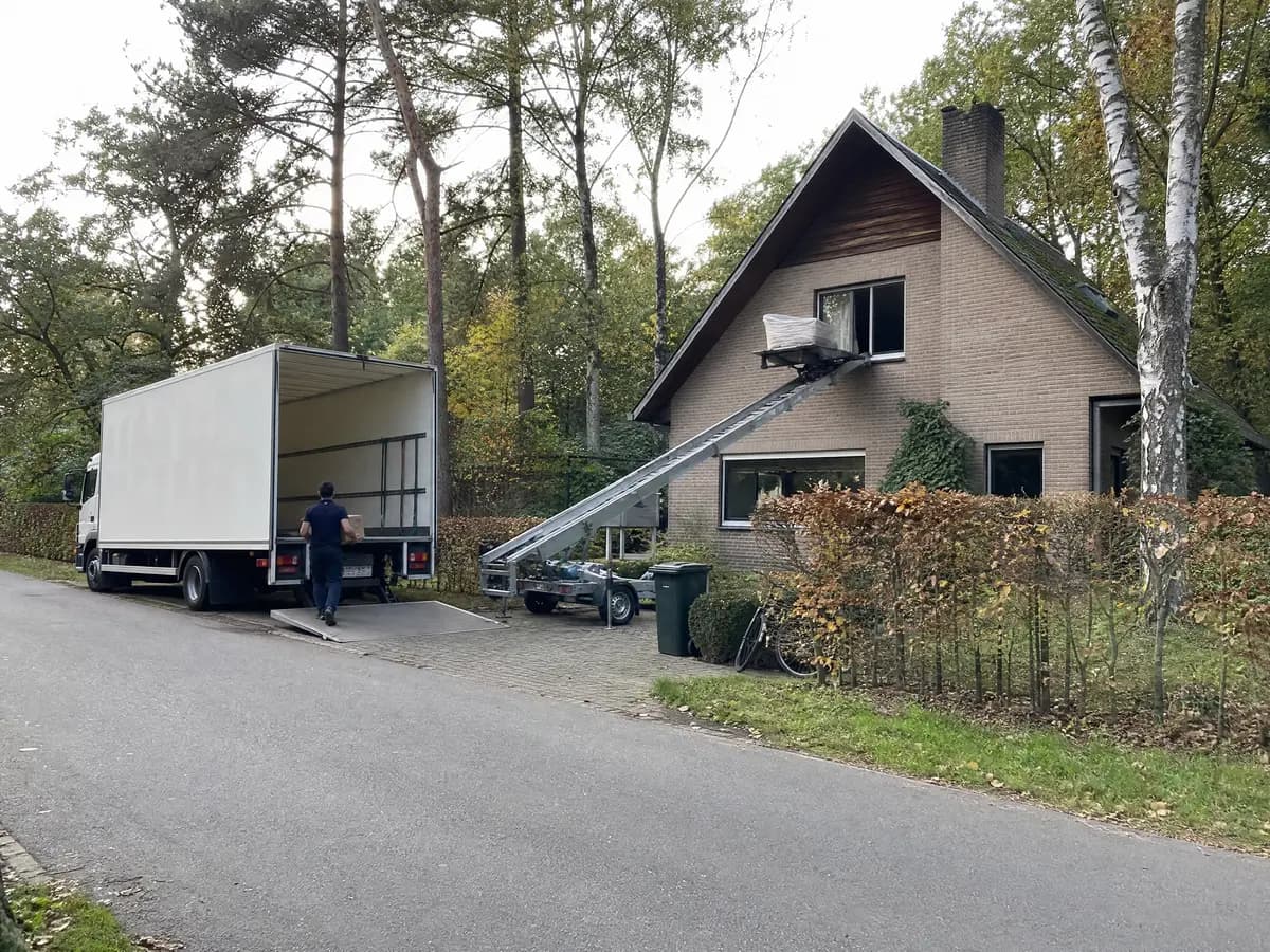 Verhuisfirma Mol: verhuiswagen op de oprit en ladderlift aan een woning in Mol