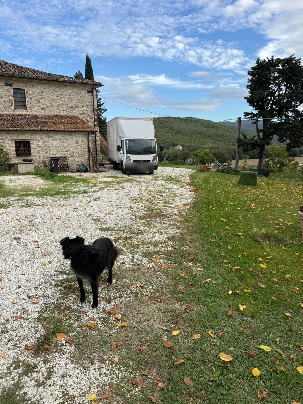 Onze verhuiswagen op het grindpad naast een stenen boerderij in Corciano bij Perugia