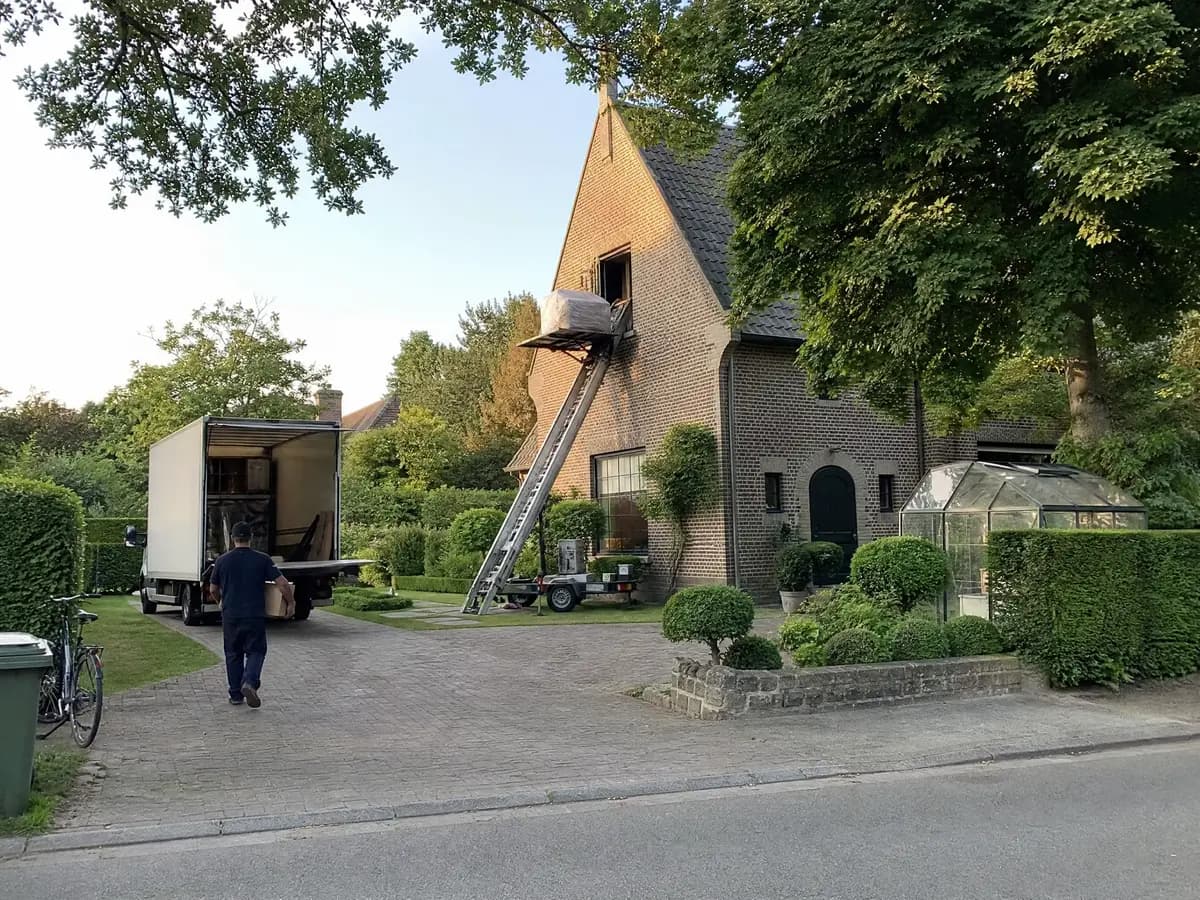 Verhuisfirma Boechout: verhuiswagen op de oprit en ladderlift aan een woning in Boechout