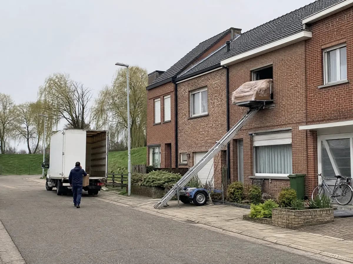 Verhuisfirma Bornem: verhuiswagen op de oprit en ladderlift aan een woning in Bornem
